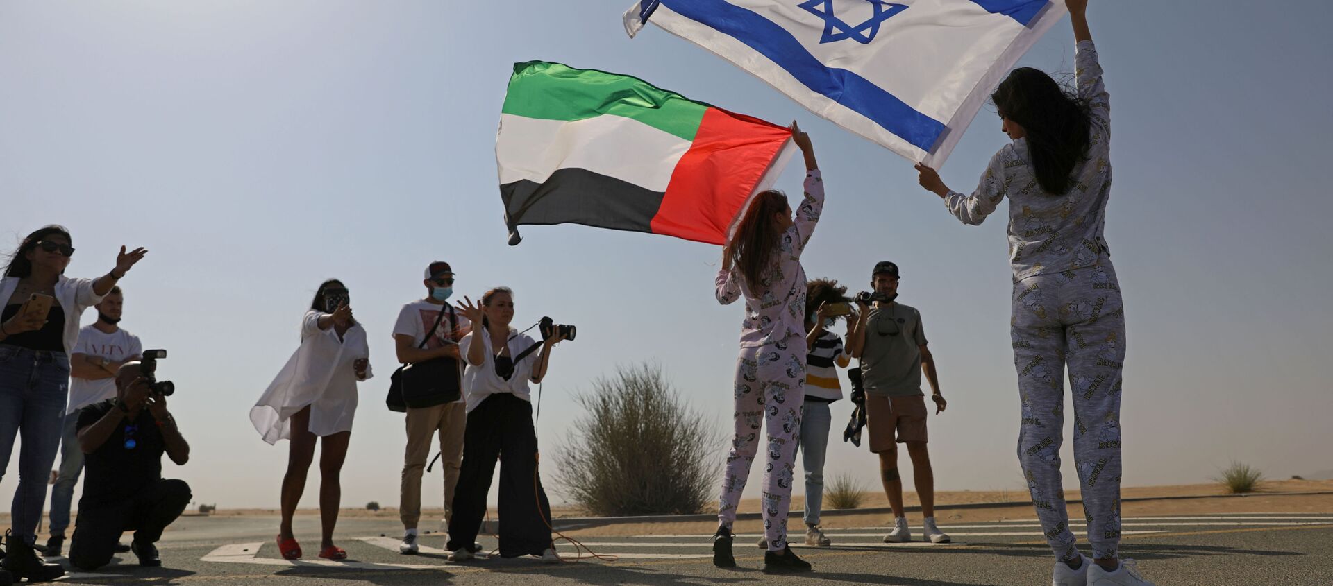 İsrail bayrağını omzunda taşıyarak Dubai'nin çöl bölgelerinde poz veren Tager'e, burada ikamet eden Rus Anastasia Bandarenka de BAE bayrağı ile eşlik etti.  - Sputnik Türkiye, 1920, 11.03.2021