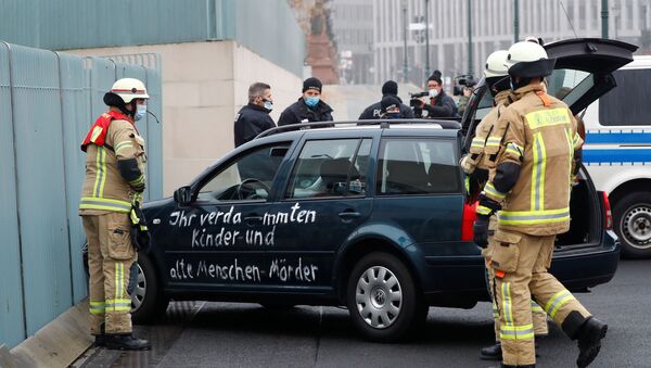 Almanya'nın başkenti Berlin'de Angela Merkel'in ofisinin bulunduğu başbakanlık binasının dış kapısına çarpan ve üzerinde sloganlar yazılı bulunan araba - Sputnik Türkiye