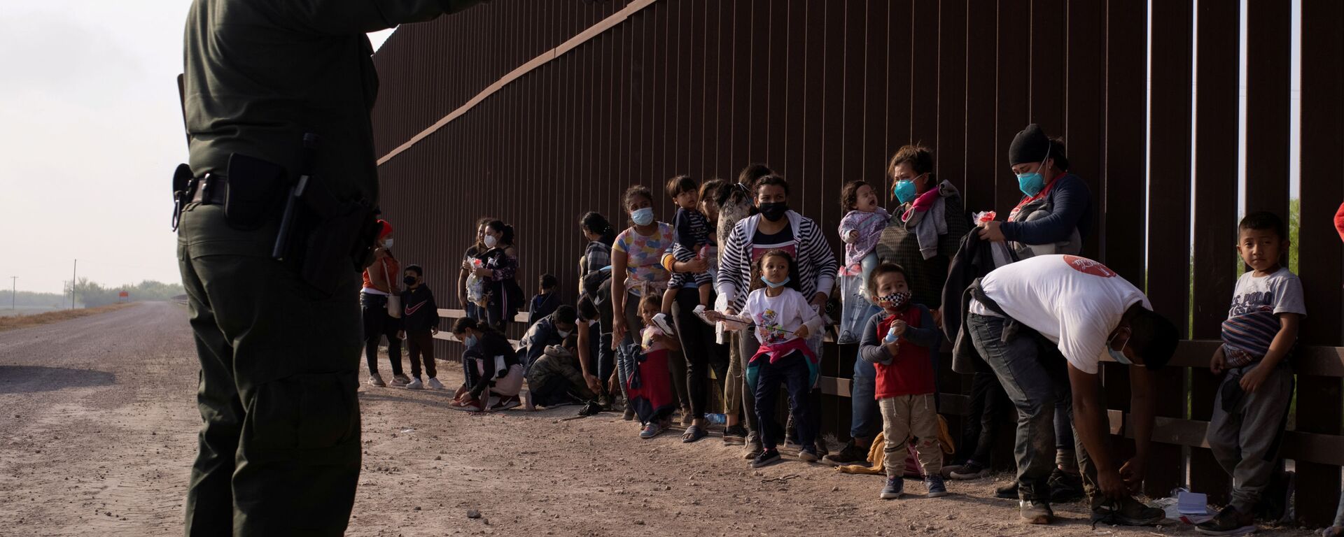 Meksika'dan tekneyle Rio Grande nehrini geçerek ABD sınırına varan göçmenleri duvar önünde sıraya dizen ABD'li federal sınır koruma ajanları (Penitas, Teksas) - Sputnik Türkiye, 1920, 22.03.2021