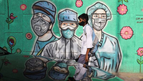 Hindistan başkenti Yeni Delhi'de insanlar, koronavirüs pandemisiyle mücadele eden sağlık çalışanlarının resmedildiği graffitinin önünden geçerken - Sputnik Türkiye