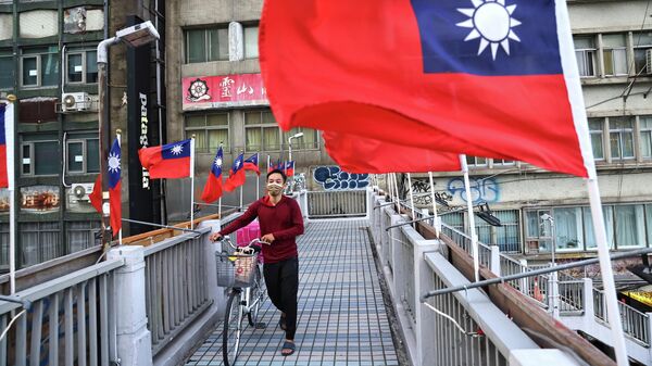 Tayvan başkenti Taipei'de Tayvan Ulusal Günü'nde bayraklar arasından geçen bir vatandaş - Sputnik Türkiye