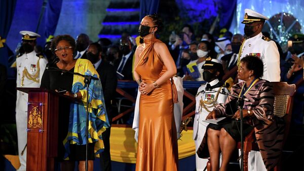 Britanya Kraliçesi 2. Elizabeth'i devlet başkanı statüsünden çıkararak dünyanın en yeni cumhuriyeti olan Barbados'ta Başbakan Mia Mottley (önde ayakta) ve Devlet Başkanı Sandra Mason (oturan), ünlü şarkıcı Rihanna'ya ulusal kahraman unvanını verirken - Sputnik Türkiye