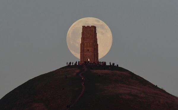 İnsanlar İngiltere&#x27;de Glastonbury Tor tepesindeki Aziz Michael kulesinin arkasından ayın doğuşunu izledi - Sputnik Türkiye