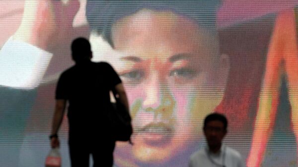 Kuzey Kore'nin 4 Temmuz 2017'deki uzun menzilli kıtalararası balistik füze denemesiyle ilgili Tokyo'daki monitörlerden akan ve Kuzey Kore lideri Kim Jong-un'u gösteren görüntüler önünden yürüyen Japonlar - Sputnik Türkiye