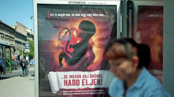 AB fonlarının kürtaj karşıtı kampanyaya aktarıldığı Macaristan'da bir cenini Beni karşılamaya hazır değilsen bile bırak yaşayayım ve beni evlat edinsinler derken gösteren posterin asıldığı bir otobüs durağı (Mayıs 2011) - Sputnik Türkiye