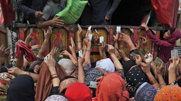 Pakistan'da hükümet, kayıtlı ihtiyaç sahiplerine Ramazan ayında tüketilmesi amacıyla un dağıttı. Fotoğrafta, kimlik kartını göstererek un yardımından yararlanmak isteyen Pakistanlı kadınlar görülüyor. - Sputnik Türkiye