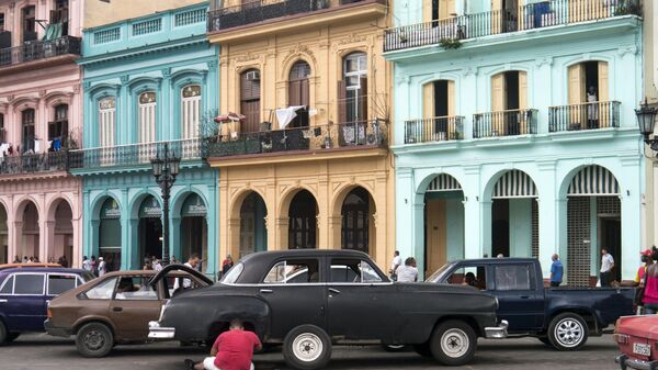 Küba başkenti Havana'nın İspanya sömürgeciliği döneminden kalma yapıları önünde eski arabaları tamir edenler - Sputnik Türkiye