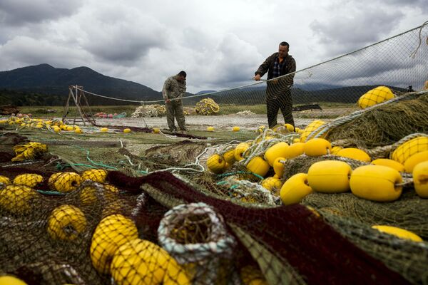 Kuril adaları kıyısında balıkçılar ağlarını tamir ederken. - Sputnik Türkiye