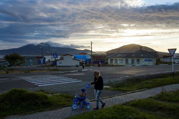 Kunaşir adasındaki Yujno-Kurilsk kenti merkezinde bir kadın çocuğuyla gezerken. - Sputnik Türkiye