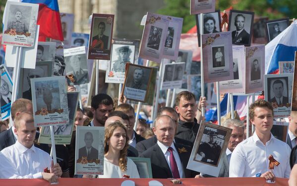 Rusya Devlet Başkanı Vladimir Putin, babası Spiridon oğlu Vladimir’in portresiyle, Kızıl Meydan'da düzenlenen ‘Ölümsüz Alay’ yürüyüşünde. - Sputnik Türkiye
