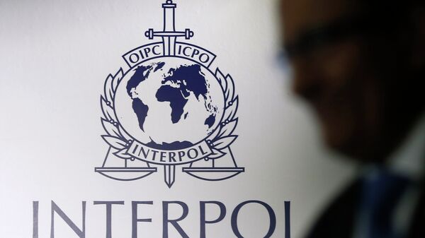 A man passes an Interpol logo during the handing over ceremony of the new premises for Interpol's Global Complex for Innovation, a research and development facility, in Singapore September 30, 2014 - Sputnik Türkiye