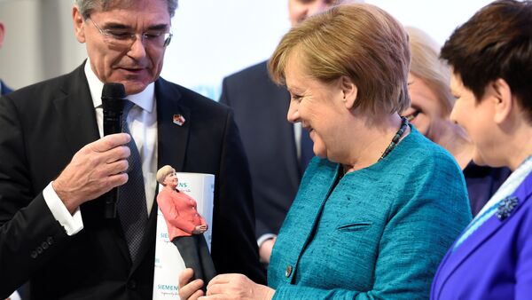 Angela Merkel elinde kendisinin üç boyutlu mini heykelini itutarken - Sputnik Türkiye