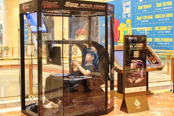 AVM ziyaretçisi, Çin'de alış-veriş merkezinde kullanılan 'yorgun koca dinleme kabininde' video oyunları oynarken. Çin, Şanghay. - Sputnik Türkiye