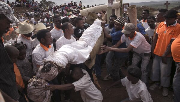 People carry a body wrapped in a sheet as they take part in a funerary tradition called the Famadihana in the village of Ambohijafy, a few kilometres from Antananarivo, on September 23, 2017 - Sputnik Türkiye