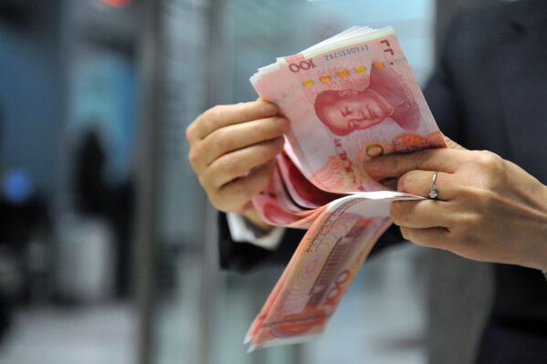 A bank employee counts 100-yuan banknotes at a bank in Hangzhou, east China's Zhejiang province on December 1, 2015. - Sputnik Türkiye