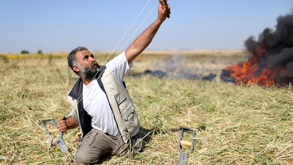 Gazze'de 'Toprak Günü' nedeniyle yapılan gösterilerde sınırdaki İsrail askerlerine taş atan bir Filistinli - Sputnik Türkiye