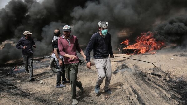 Palestinian protesters pull on a burning tire during clashes with Israeli forces on April 20, 2018, east of Khan Yunis, in the southern Gaza Strip during mass protests along the border of the Palestinian enclave, dubbed The Great March of Return, which has the backing of Gaza's Islamist rulers Hamas - Sputnik Türkiye