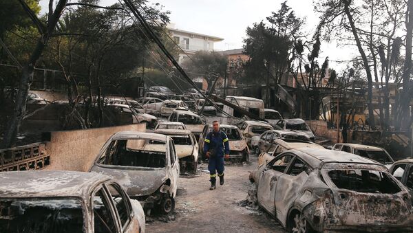 Yunanistan'ın başkenti Atina'nın sahil bölgesi Mati'de yangın felaketinde kavrulan araçlar arasında itfaiye eri - Sputnik Türkiye