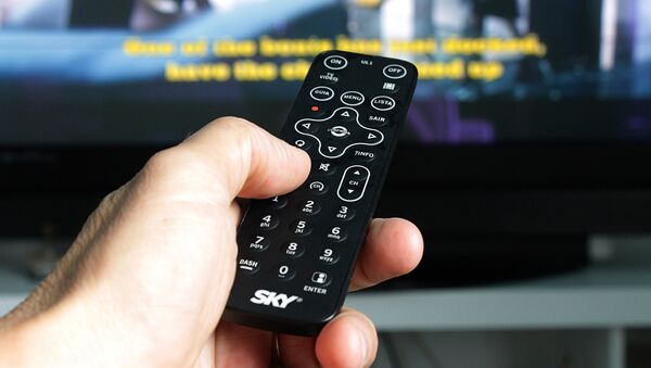 A man holding a remote control, watching TV - Sputnik Türkiye