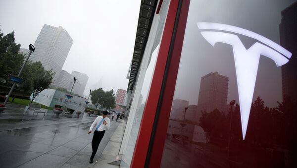 A man walks near a logo of Tesla outside its China headquarters at China Central Mall in Beijing, China July 11, 2018 - Sputnik Türkiye