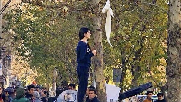 İran'da Vida Movahed'in 27 Aralık 2017'de başkenti Tahran'ın Enghelab (İnkılap) Sokağı'nda bir telekom kutusunun üzerine çıkıp beyaz başörtüsünü bağladığı sopayı bayrak gibi sallaması, kadınların örtünmeyi zorunlu kılan yasaya yönelik protestolarının simgesi haline geldi. - Sputnik Türkiye