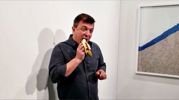 Performans sanatçısı David Datuno, İtalyan sanatçı Maurizio Cattelan’ın 120 bin dolara satılan ‘duvara bantlanmış muz’ çalışmasını yedi. - Sputnik Türkiye