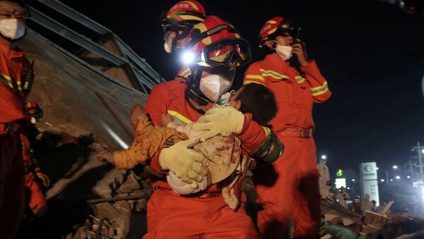 A worker wearing a face mask rescues a child at the site where a hotel being used for the coronavirus quarantine collapsed, in the southeast Chinese port city of Quanzhou, Fujian province, China March 8, 2020. China Daily via REUTERS ATTENTION EDITORS - THIS IMAGE WAS PROVIDED BY A THIRD PARTY. CHINA OUT. - Sputnik Türkiye