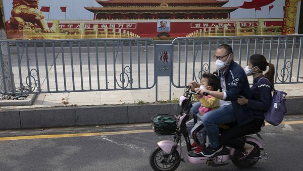 Residents wearing masks pass by government propaganda posters featuring Tiananmen Gate in Wuhan. - Sputnik Türkiye